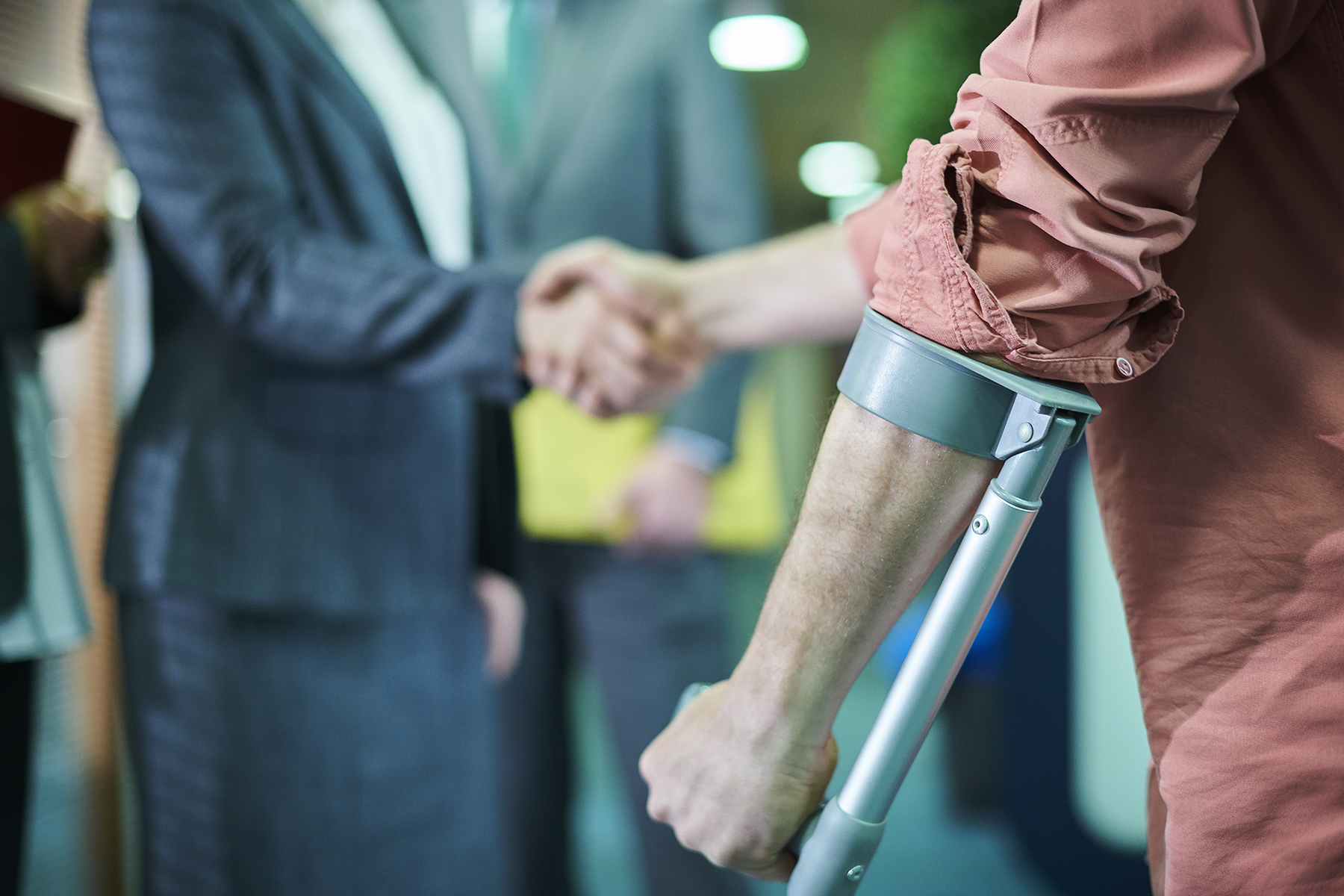 person supported by crutches shaking hands with another person