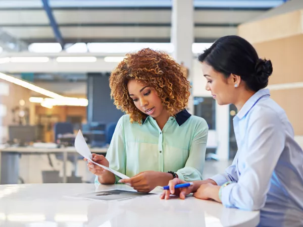 Two women sitting at a table going over forms.