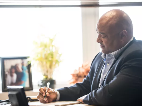 A man sitting at his desk writing in a notebook.