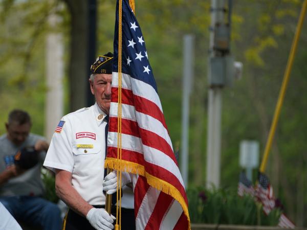 A veteran holding the American flag marching in a Memorial Day parade.