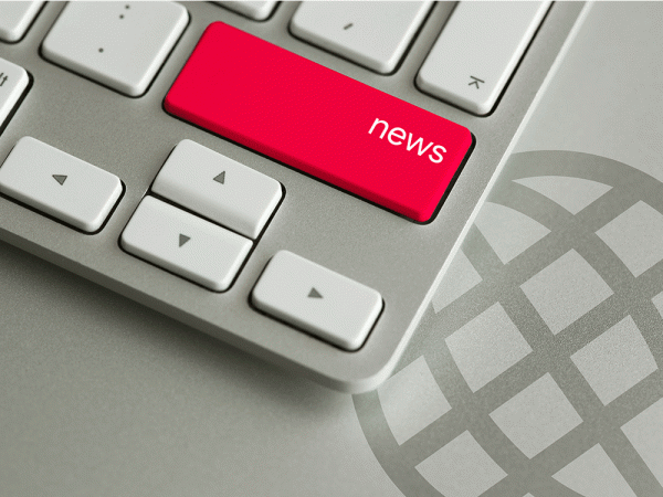 The lower right corner of a keyboard showing a big red key with the word "news" on the key. The keyboard is sitting on top of the world wide web symbol.