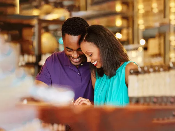 A man and woman in a store with their heads close together looking down at a ring on her finger.