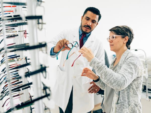 Woman selecting new eyeglasses with help of a doctor