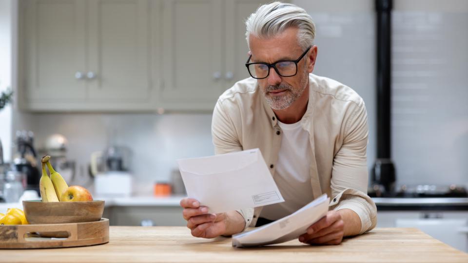 Guy in glasses reading and holding white papers