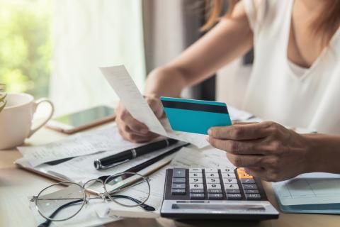 Person with calculator, papers, and glasses on table