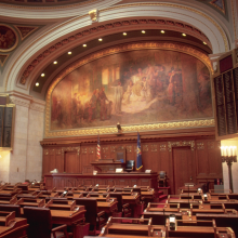Wisconsin legislative sessions room facing the front of the room with the large mural above the leader's desk.