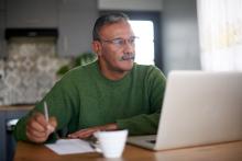 Green sweater older man at computer