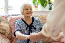 "elderly woman holding hands with caregiver"