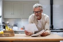 Guy in glasses reading and holding white papers