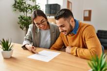 Two employees smiling while reading a document that one is point to