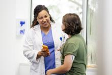 Female doctor discusses with patient who has a glucose monitor pod on her left arm.