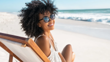 Woman wearing sunglasses on a beach.
