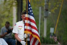 A veteran holding the American flag marching in a Memorial Day parade.