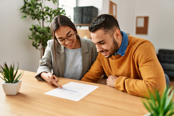 Two employees smiling while reading a document that one is pointing to