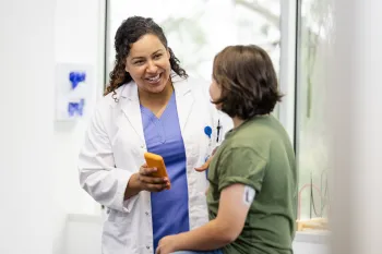 Female doctor discusses with patient who has a glucose monitor pod on her left arm.