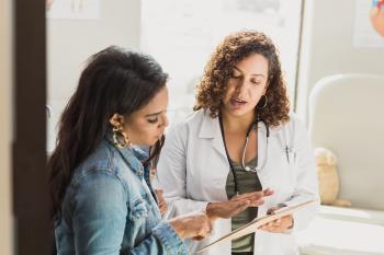Female doctor talking with female patient about chart.